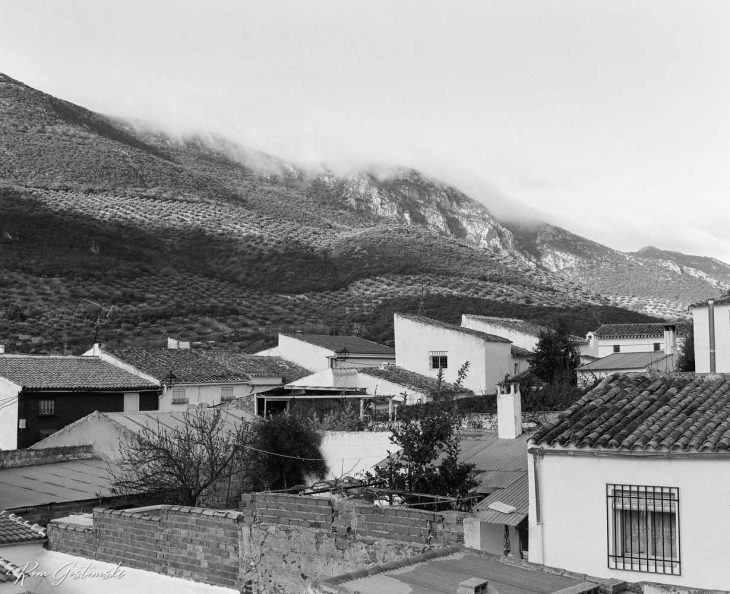 Black and white photo of village roofs. The photo was taken on an overcast day with low cloud obscuring the hills.